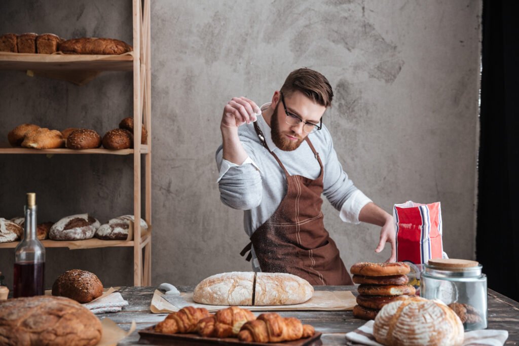 Concentrated man baker standing at bakery near bread